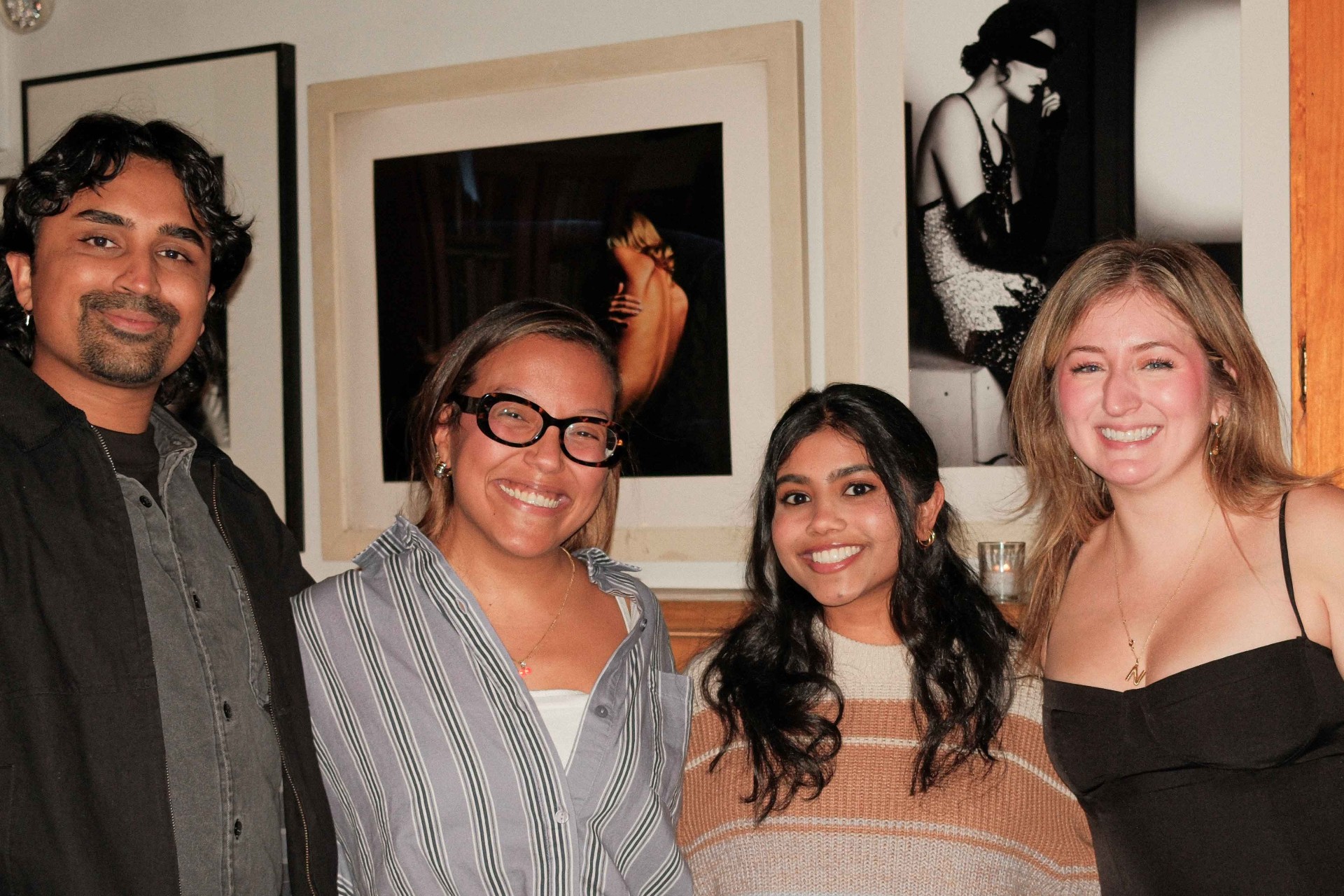 Four guests posing in front of artwork at a CX and the City dinner